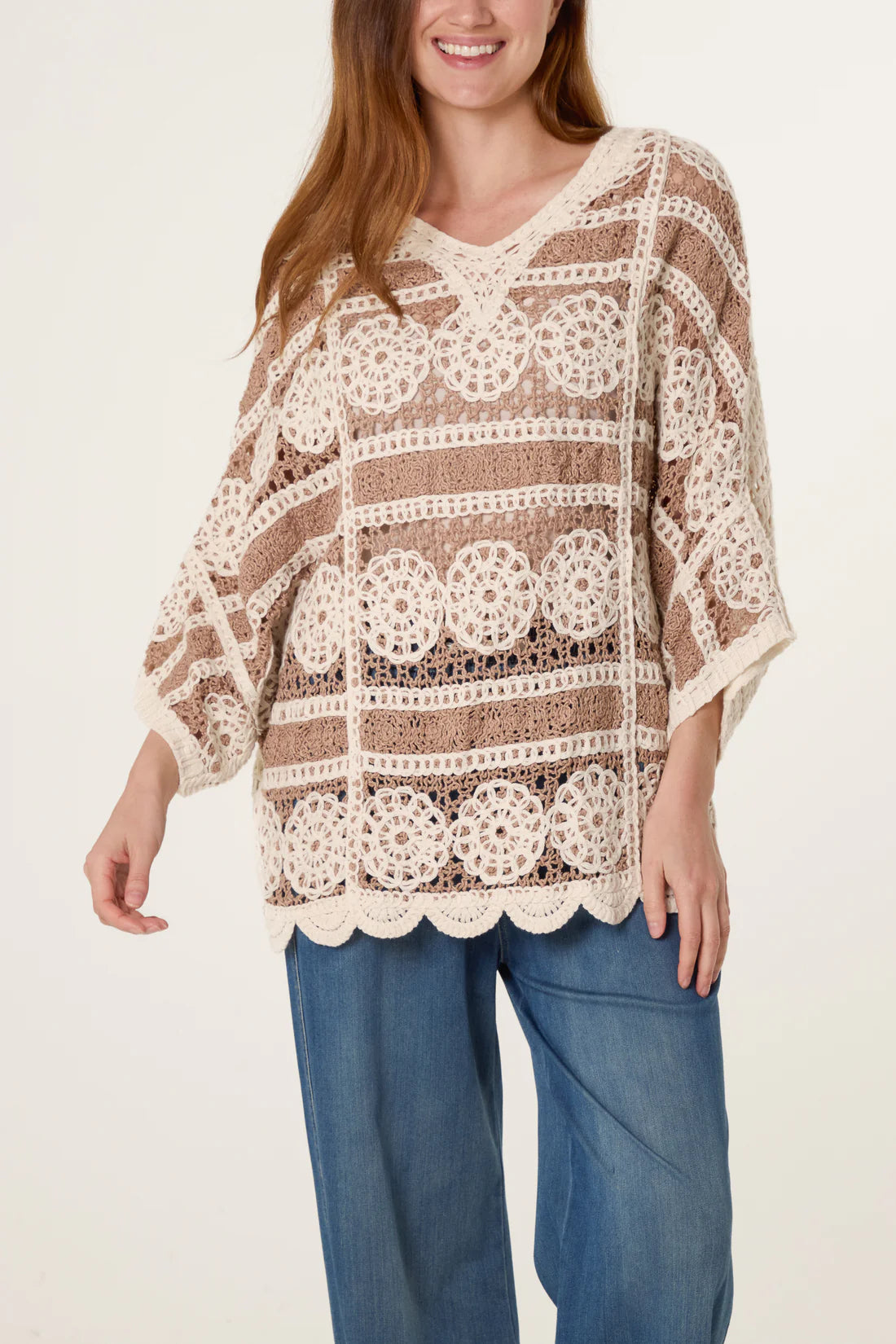 Woman wearing a Mocha and Cream Crochet Circle Scallop Edge Top and blue pants on a plain background