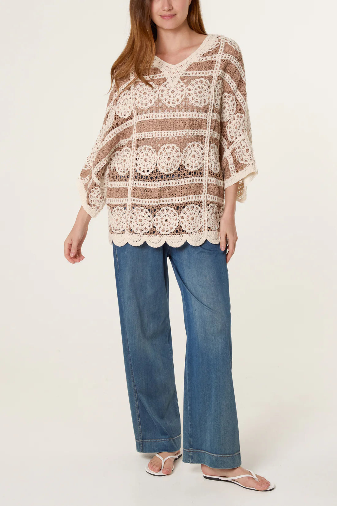 Woman wearing a Mocha and Cream Crochet Circle Scallop Edge Top and blue jeans on a white background