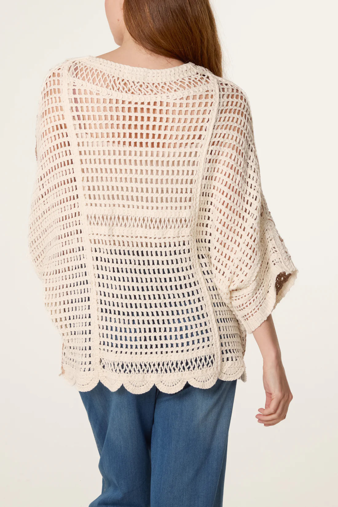 Back view Woman wearing a Mocha and Cream Crochet Circle Scallop Edge Top and blue pants on a white background