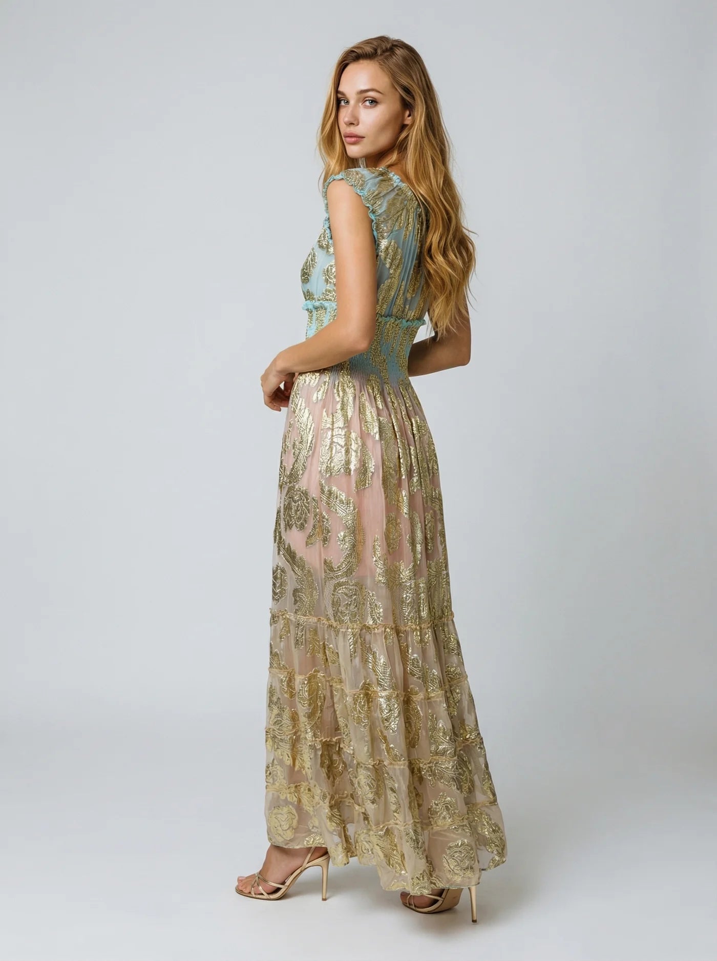 Woman wearing a long, patterned dress on a white background
