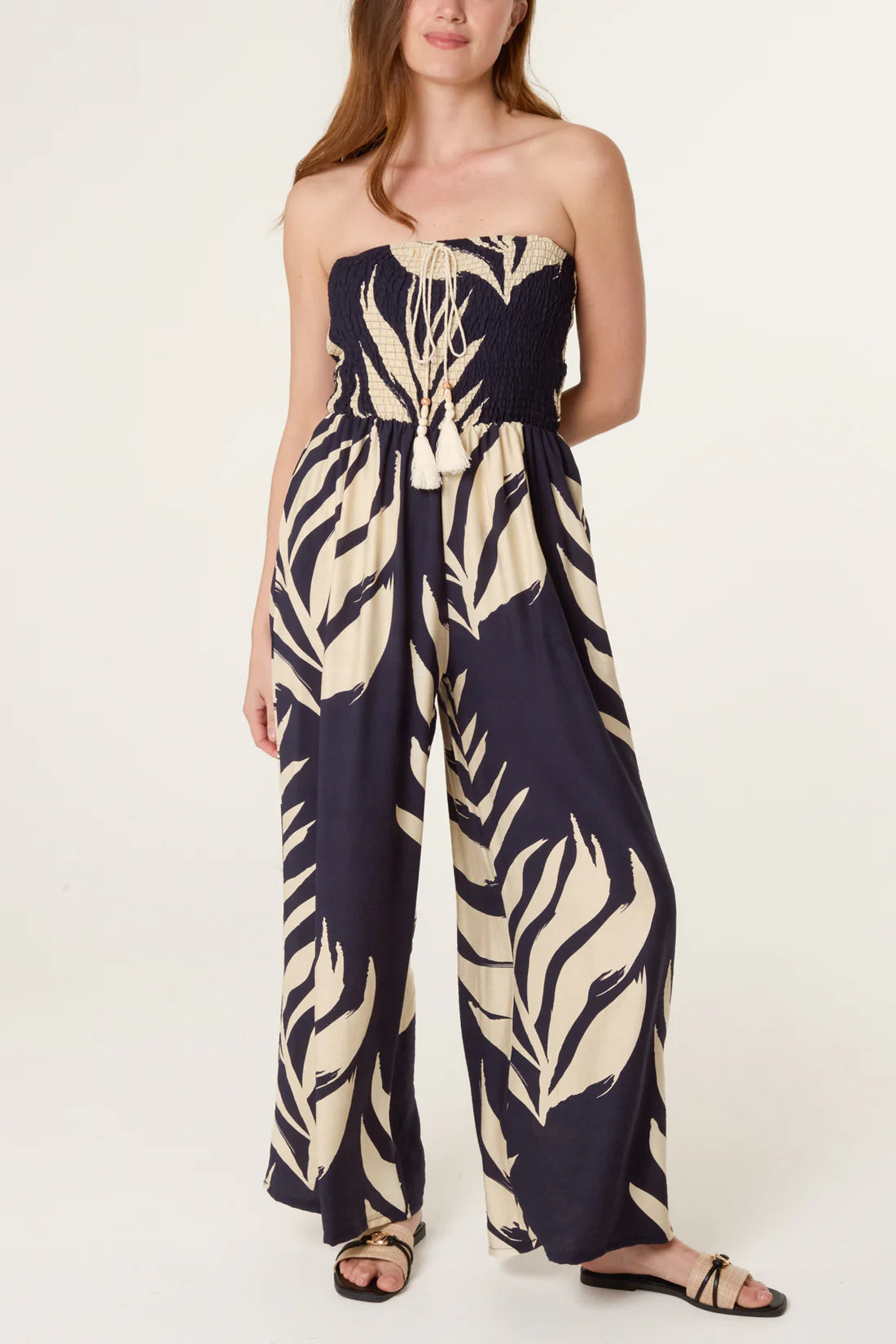 Woman wearing a Navy Bandeau Tassel Leaf Print Jumpsuit with a leaf pattern on a white background