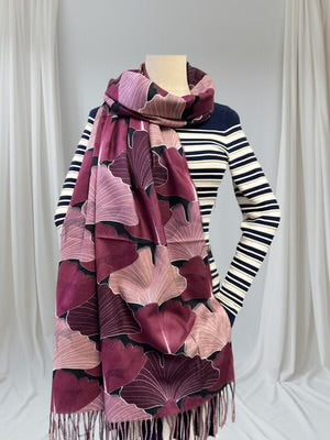 Mannequin wearing a striped sweater with a large purple patterned scarf draped over it against a white curtain background.