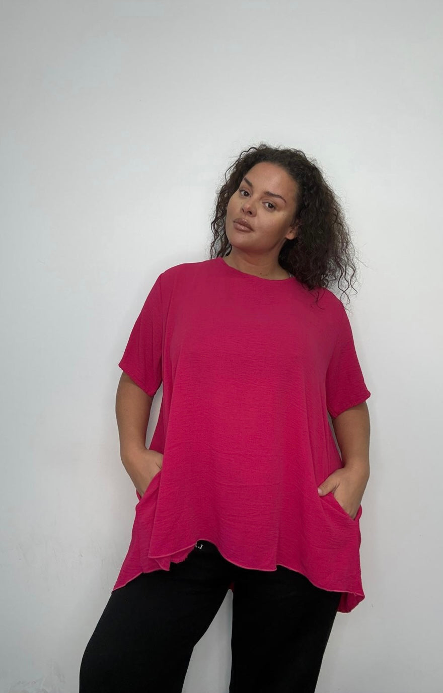 Person wearing a pink Plus Size Pleated Back Oversized T-Shirt with Pockets and black pants against a white background