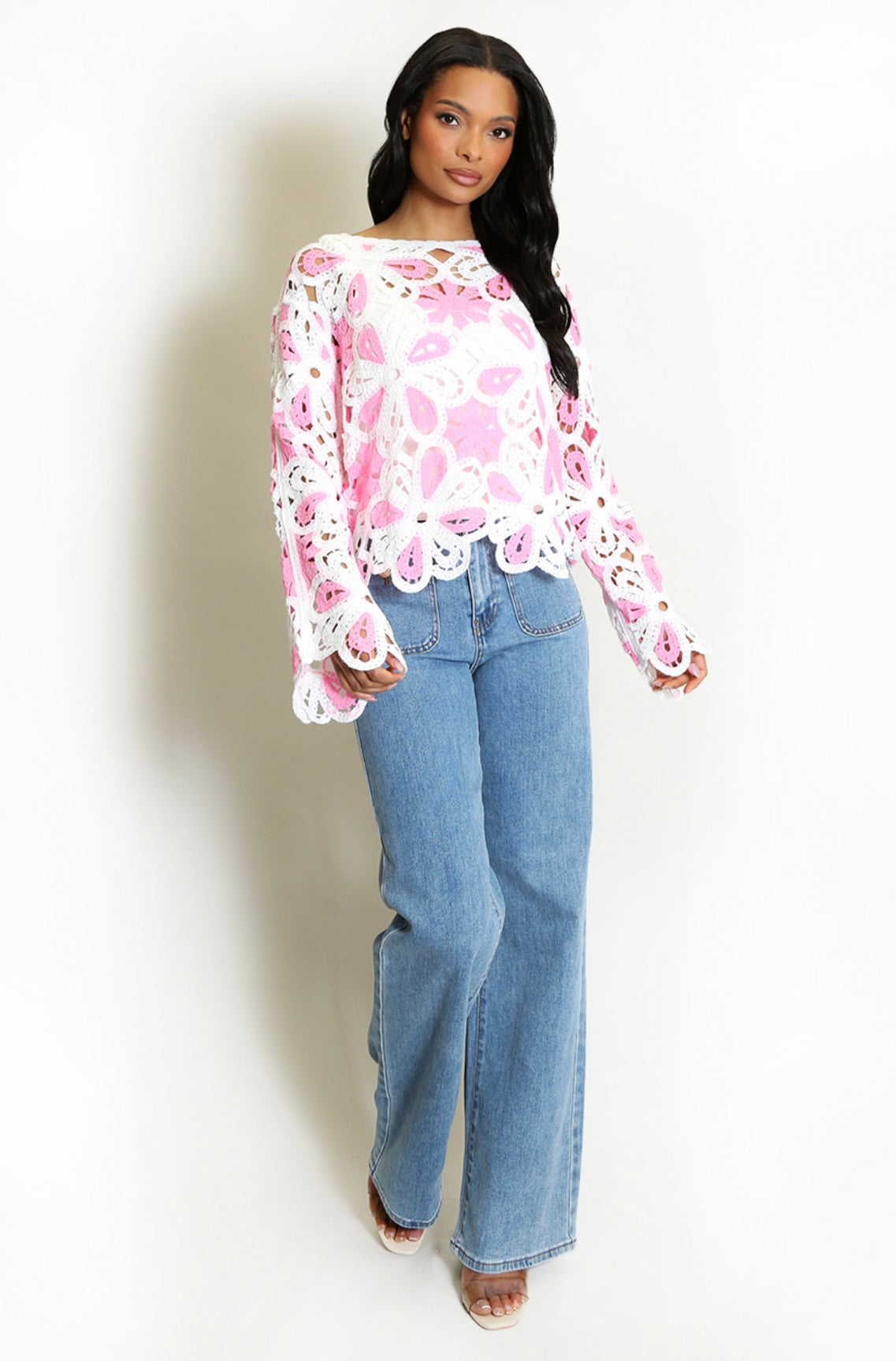 Woman wearing a Pink and White Floral Crochet Jumper and blue jeans on a white background