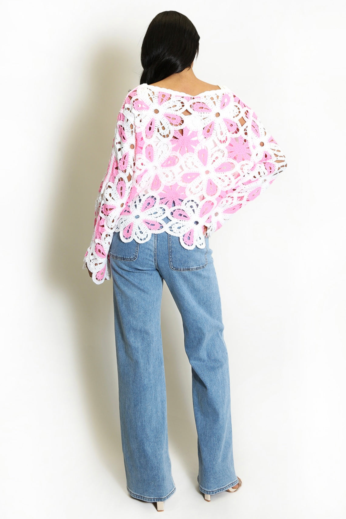 Back of Person wearing a Pink and White Floral Crochet Jumper and blue jeans on a white background