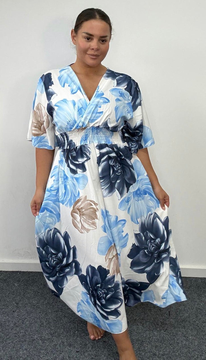 Woman wearing a blue and white floral dress against a plain background