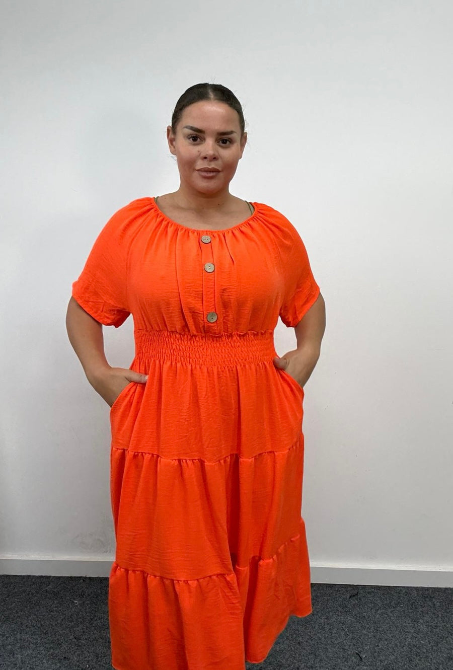Woman wearing a Plus Size Orange Button Detail Tiered Midi Dress with Pockets against a plain white background