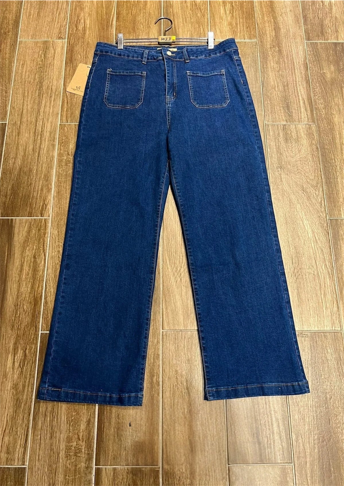 Pair of Plus Size Wide Leg Two Front Pocket Voggo Jeans on a hanger against a wooden floor background