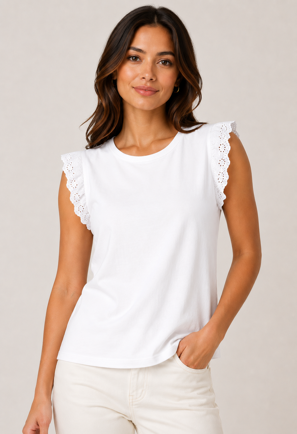 Woman wearing a white sleeveless top with lace details on a plain background