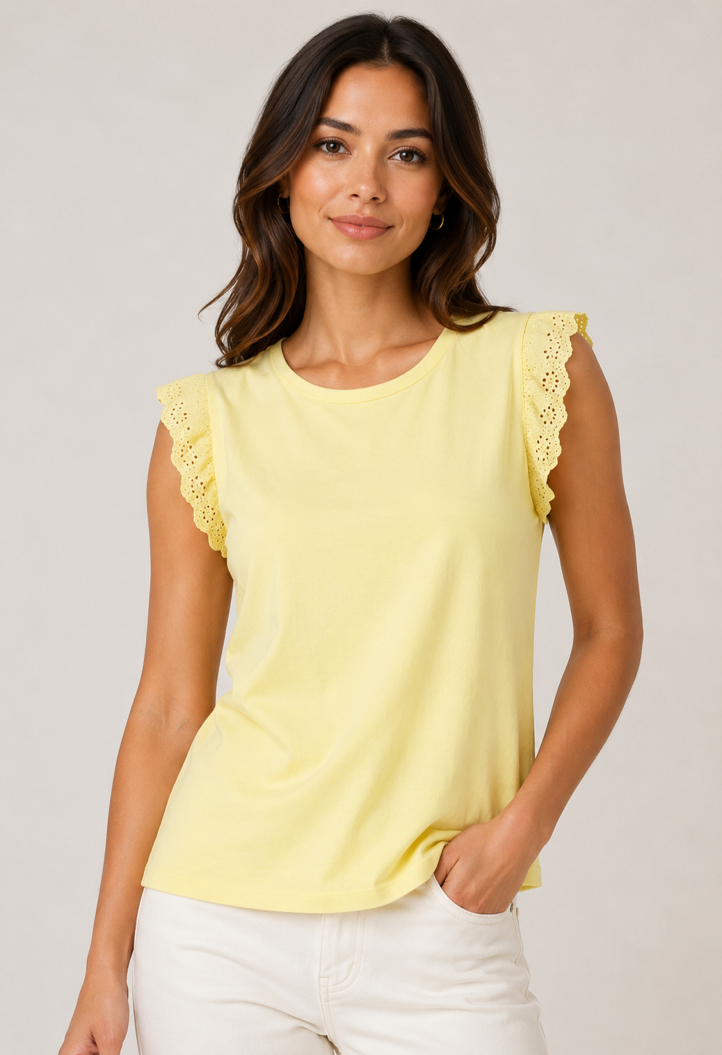 Woman wearing a yellow top with lace sleeves against a plain background