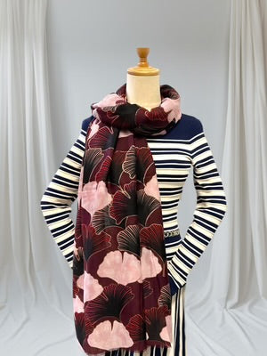 Mannequin wearing a striped sweater with a floral-patterned scarf against a white curtain background