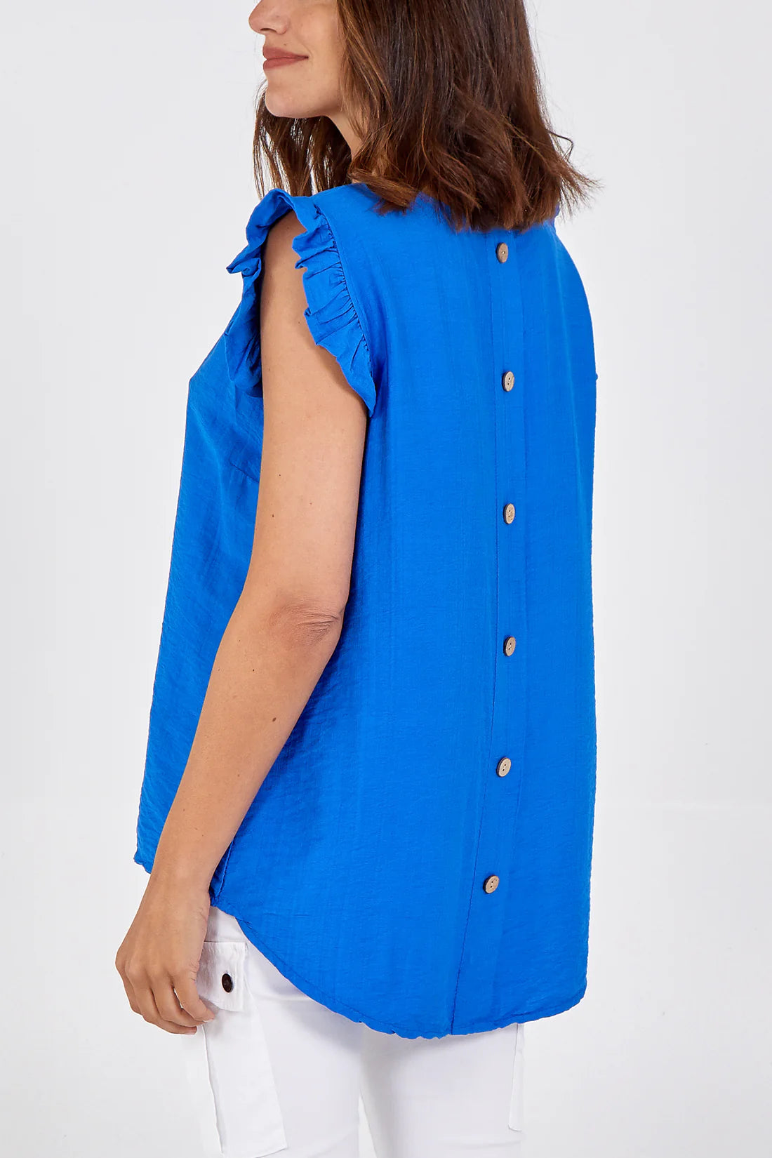 Woman wearing a blue sleeveless blouse with buttons on a white background