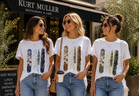 Three women wearing matching t-shirts with graphic designs in front of a restaurant.