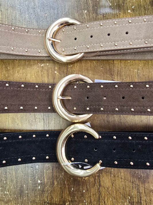 Three belts with gold buckles on a wooden surface