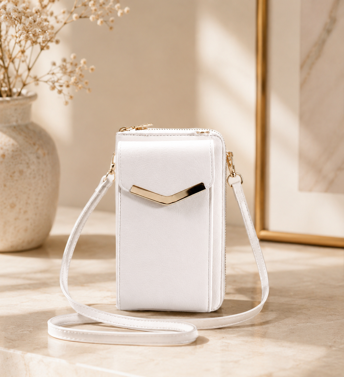 White crossbody bag with gold accent on a light wooden surface with a neutral background
