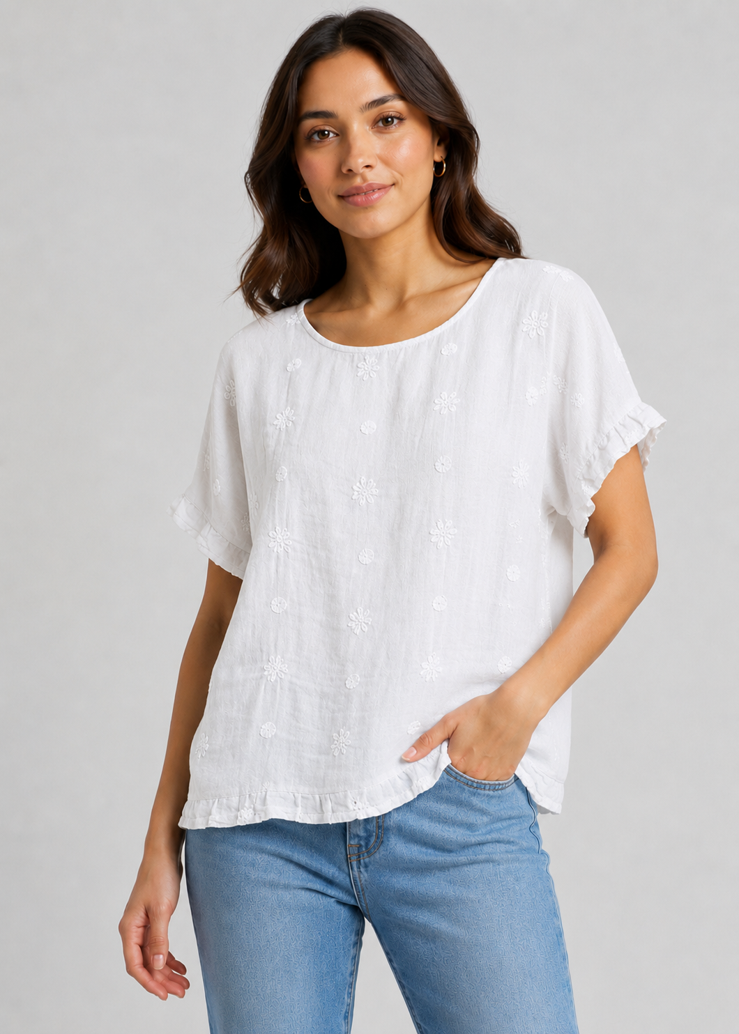 Woman wearing a white blouse and blue jeans against a gray background