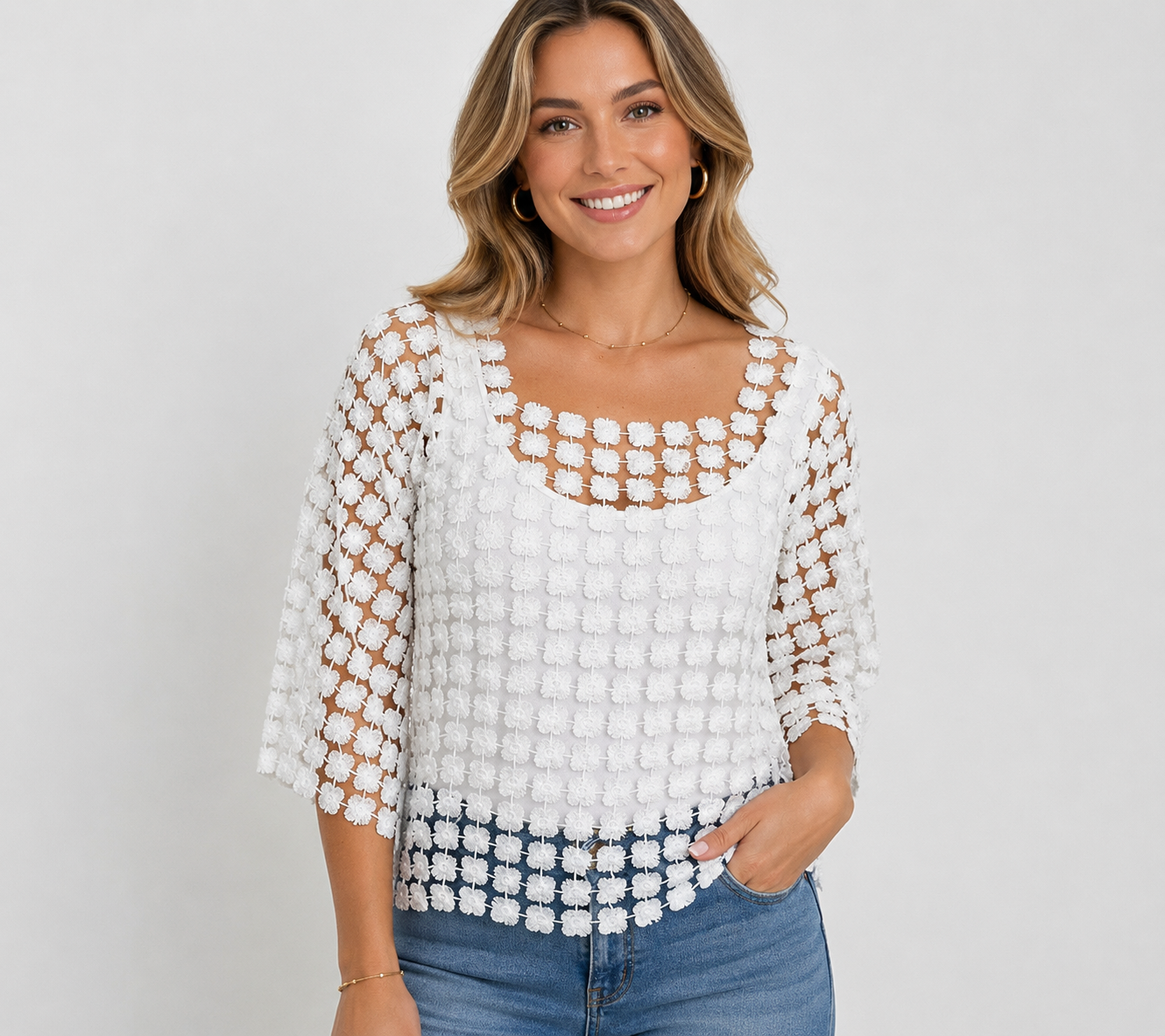 Woman wearing a white crochet top with a plain background