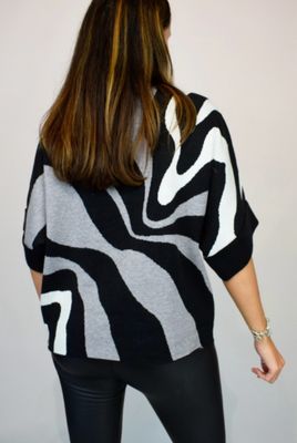 Woman Wearing Grey, Black and White High Neck Contrast Swirl Light Knit Jumper. Back View