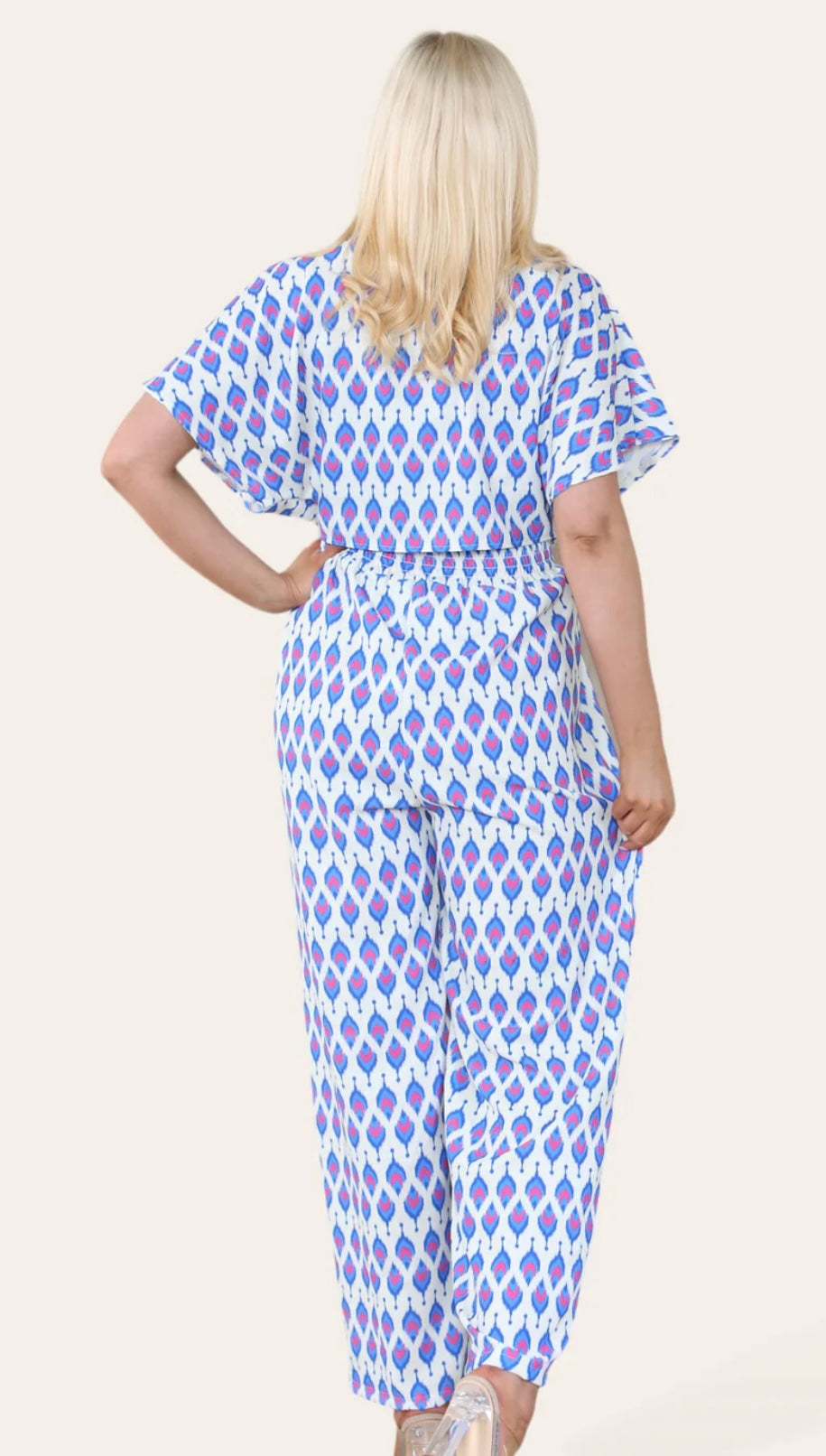 Woman Wearing Printed Geometric Jumpsuit With Bolero Jacket in Royal Blue. Back View