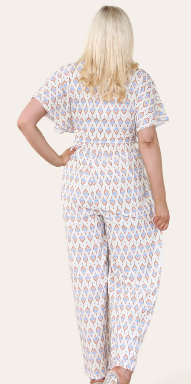 Woman Wearing Printed Geometric Jumpsuit With Bolero Jacket in Beige. Back View