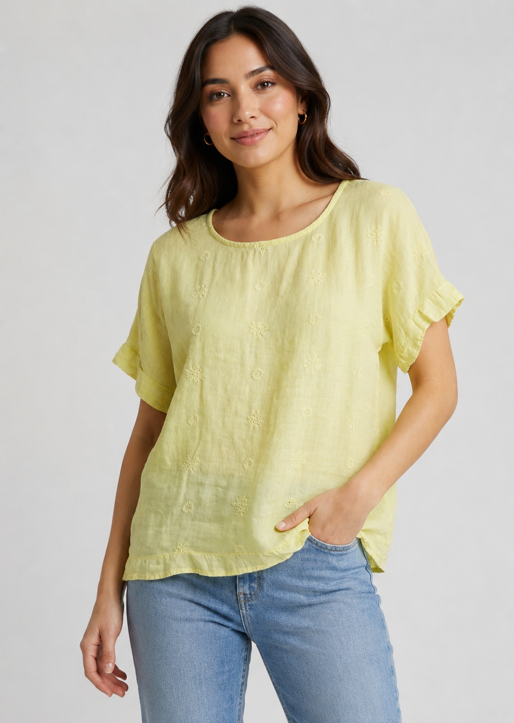 Woman wearing a yellow top and blue jeans on a plain background