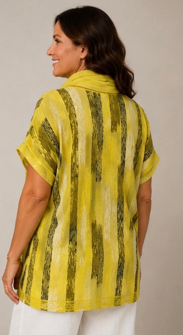 A woman shown from the back wearing a yellow short-sleeve top with vertical olive green textured stripes, paired with white pants, against a plain light gray background.